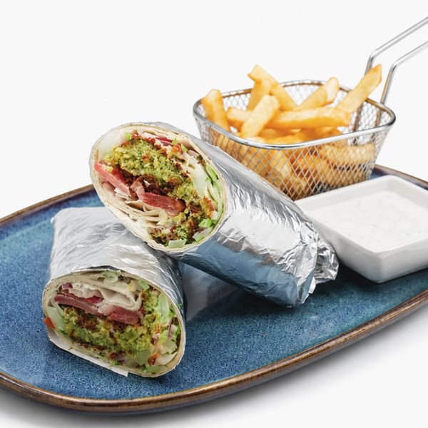 Two falafel wraps with fries in a metal basket and a side of white sauce on a blue plate.